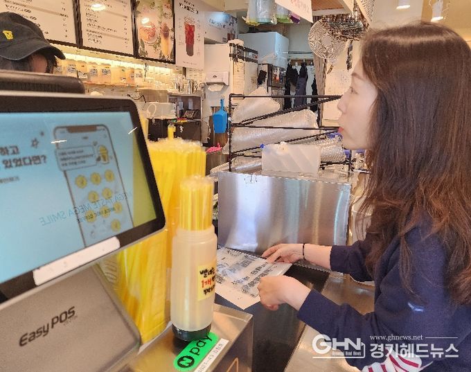 화산동 관계자가 카페를 방문해 종이팩 별도 수거 사업을 홍보하며 전용 수거 봉투를 전달하고 있다